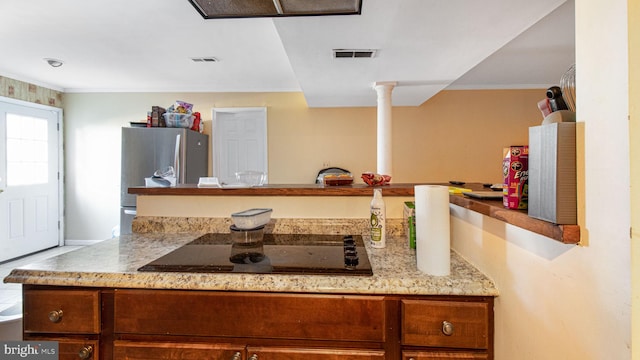 kitchen featuring black electric cooktop, visible vents, decorative columns, and freestanding refrigerator