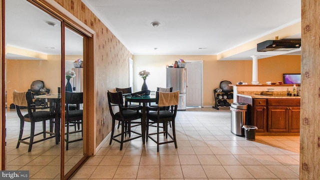 dining area featuring crown molding, light tile patterned flooring, and baseboards