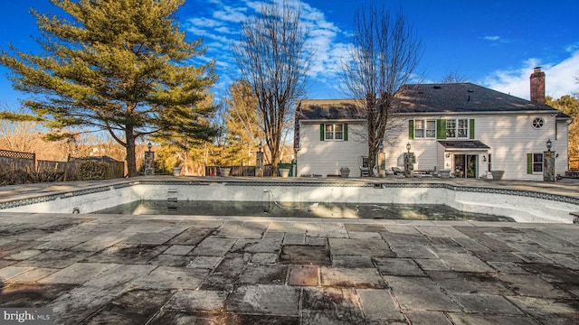 view of pool with a patio area, fence, and an empty pool