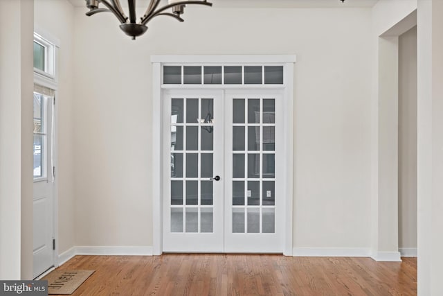 entryway featuring an inviting chandelier, baseboards, wood finished floors, and french doors