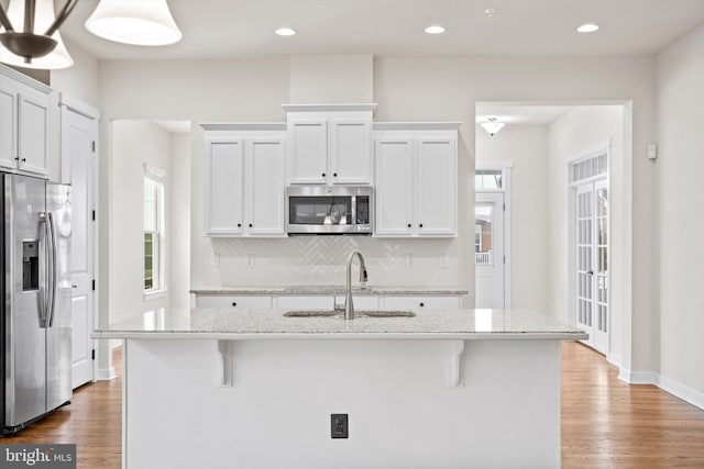 kitchen featuring appliances with stainless steel finishes, a sink, backsplash, and wood finished floors