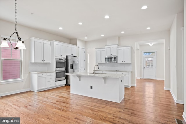 kitchen with light wood finished floors, white cabinetry, stainless steel appliances, and a breakfast bar area