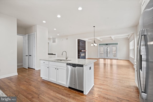 kitchen with appliances with stainless steel finishes, an island with sink, light wood-type flooring, and a sink