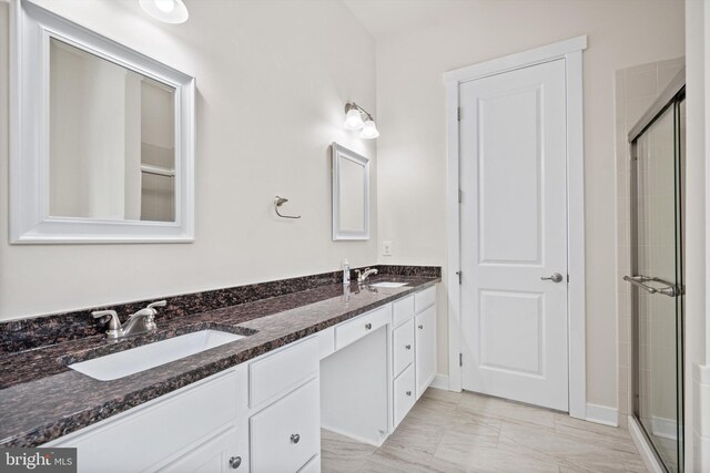 bathroom with double vanity, a stall shower, and a sink