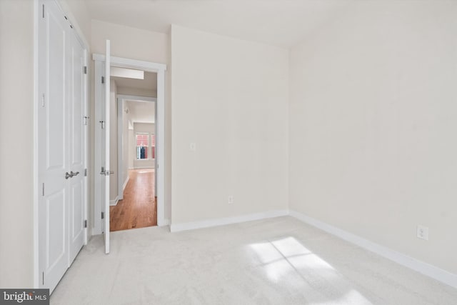 unfurnished bedroom with baseboards, a closet, and light colored carpet