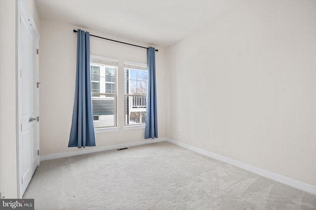 spare room featuring carpet flooring, visible vents, and baseboards