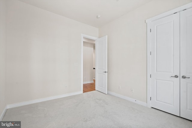 unfurnished bedroom with a closet, baseboards, and carpet flooring