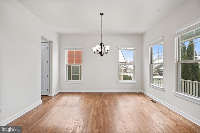 unfurnished dining area featuring light wood finished floors, visible vents, baseboards, and a notable chandelier