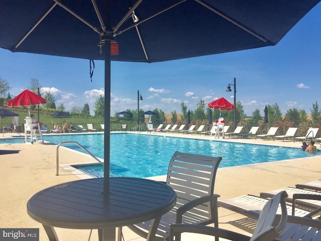 community pool with a patio area and fence