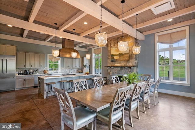 dining room featuring a stone fireplace, a healthy amount of sunlight, concrete floors, and baseboards