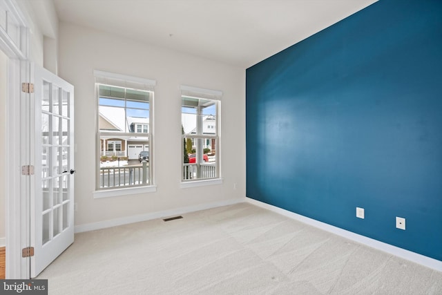 spare room with carpet flooring, visible vents, and baseboards