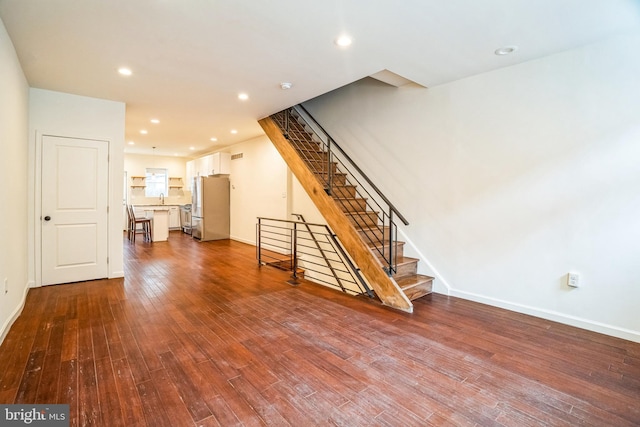 unfurnished living room featuring stairway, recessed lighting, dark wood-style flooring, and baseboards