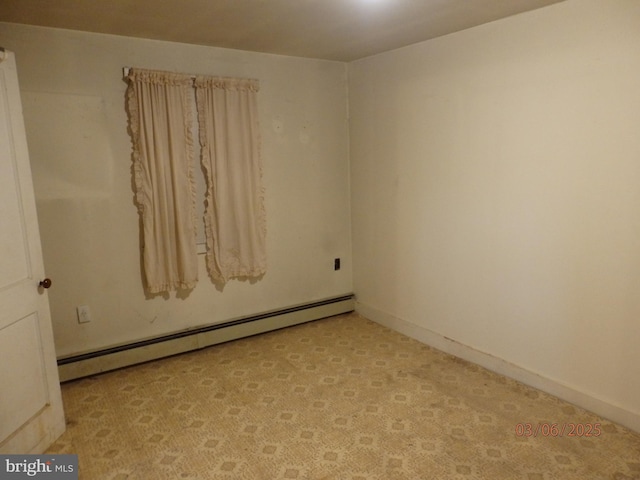 empty room featuring a baseboard heating unit, light colored carpet, and baseboards