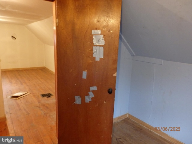 additional living space with visible vents, lofted ceiling, baseboards, and wood finished floors