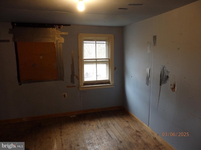 spare room with baseboards and wood-type flooring