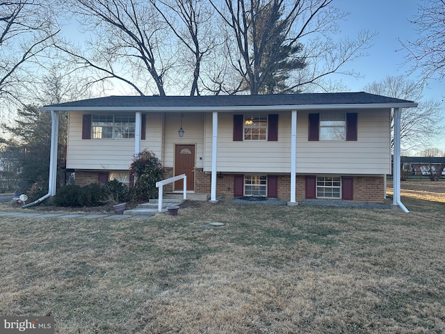 split foyer home featuring brick siding and a front lawn