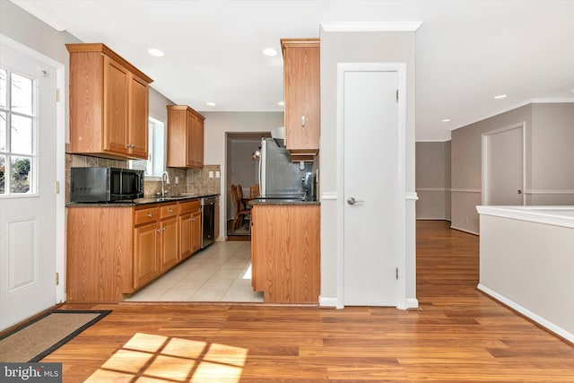 kitchen featuring light wood-style flooring, a sink, dark countertops, freestanding refrigerator, and black microwave