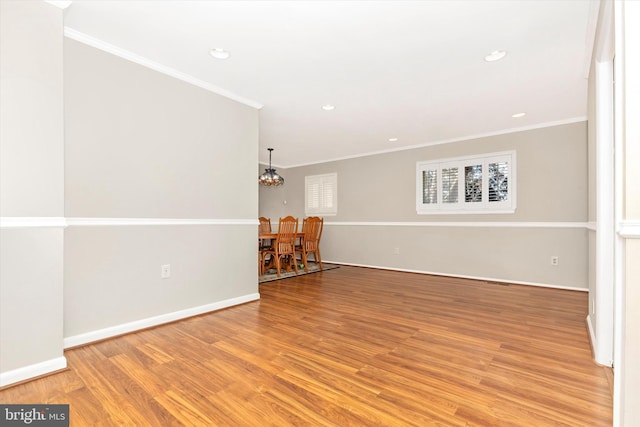 empty room with baseboards, light wood-style flooring, recessed lighting, crown molding, and a chandelier