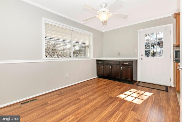 interior space featuring crown molding, a wealth of natural light, visible vents, and light wood finished floors