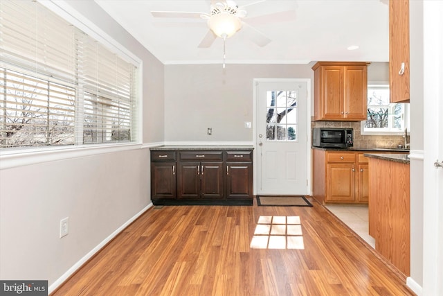 kitchen with baseboards, ornamental molding, decorative backsplash, dark countertops, and light wood-type flooring