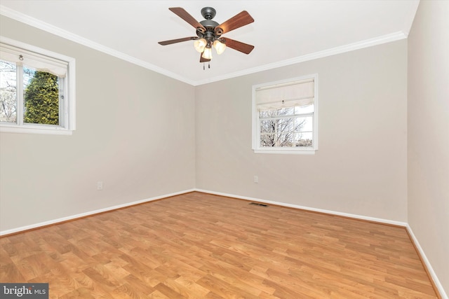 spare room featuring light wood-type flooring, visible vents, baseboards, and ornamental molding