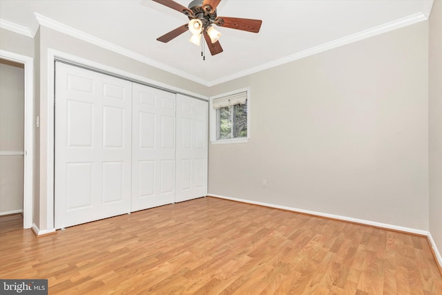 unfurnished bedroom with crown molding, light wood-style floors, baseboards, and a closet