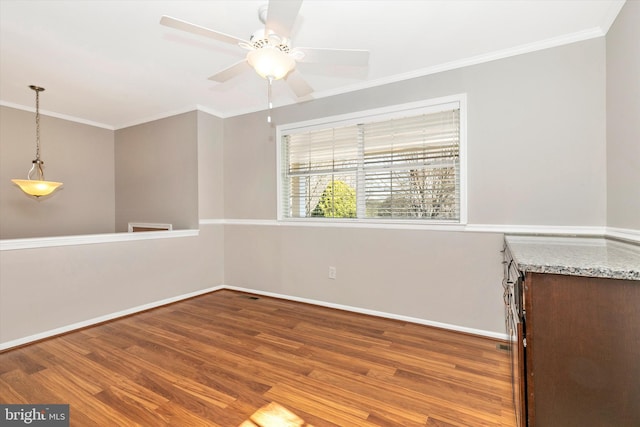 spare room with a ceiling fan, crown molding, baseboards, and wood finished floors