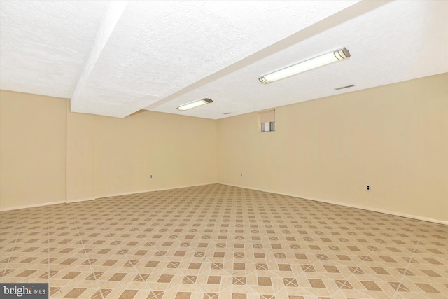 finished below grade area with visible vents, baseboards, and a textured ceiling