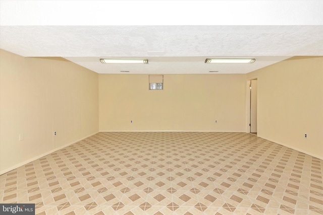 unfurnished room with baseboards and a textured ceiling