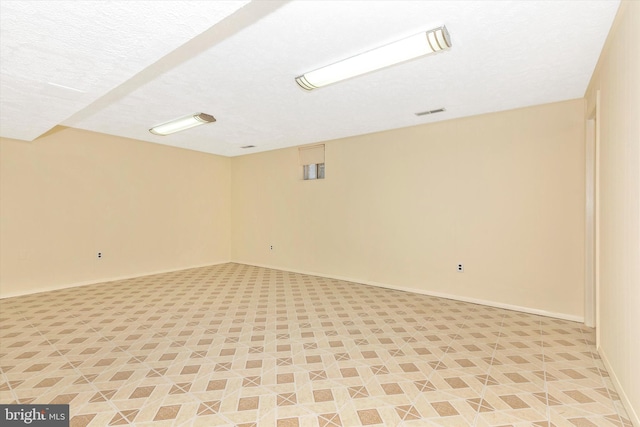 spare room with visible vents, a textured ceiling, and baseboards