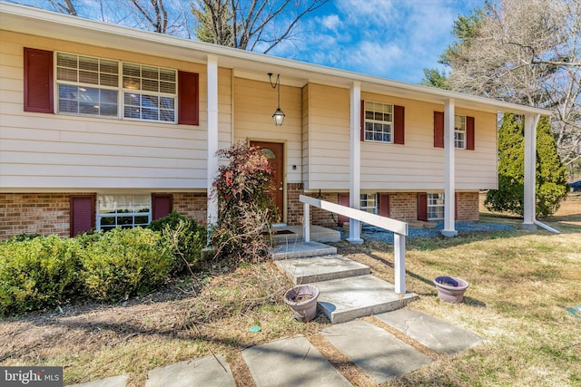 raised ranch with brick siding and a front yard