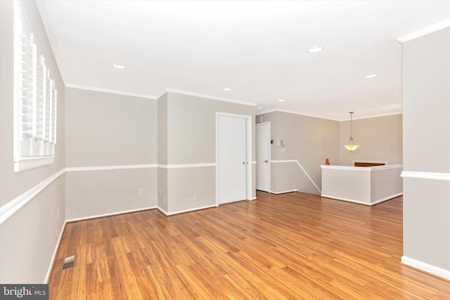 spare room with visible vents, baseboards, light wood-style flooring, and ornamental molding