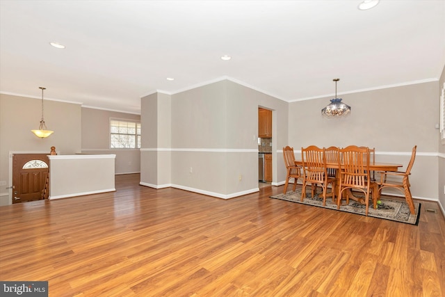 dining room featuring crown molding, light wood-style flooring, baseboards, and a chandelier