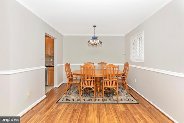 dining space with baseboards, ornamental molding, and light wood finished floors