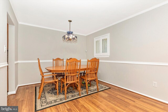 dining space featuring baseboards, a notable chandelier, wood finished floors, and crown molding