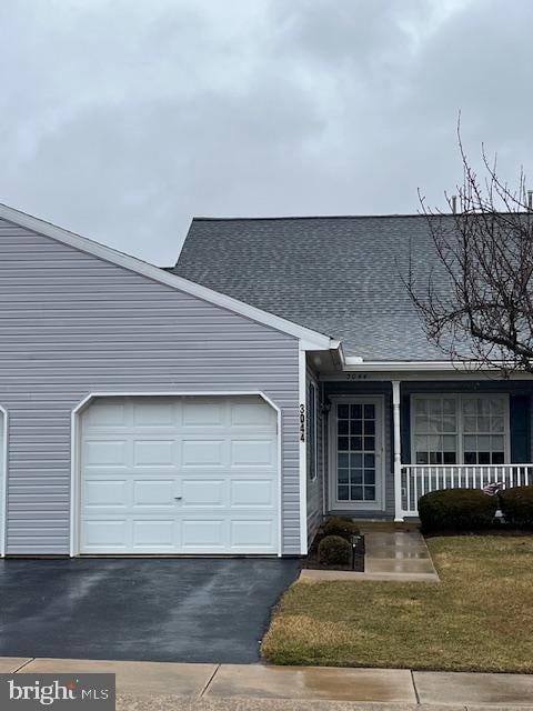 view of front of property with an attached garage, a porch, aphalt driveway, and a front yard