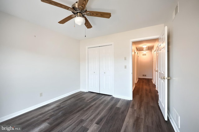 unfurnished bedroom featuring dark wood-type flooring, a closet, visible vents, and baseboards