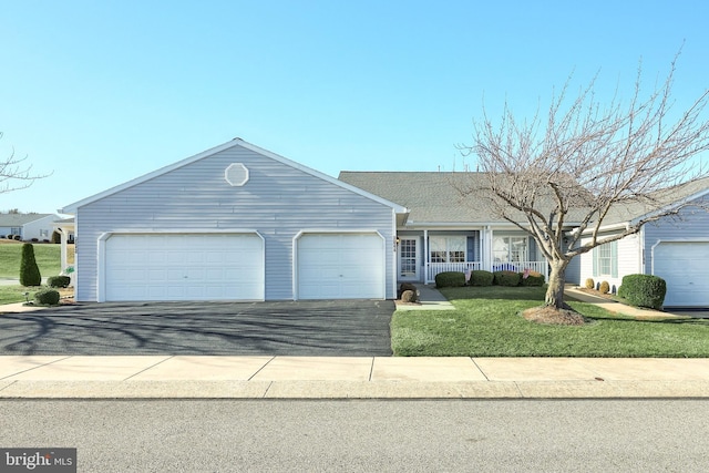 ranch-style home featuring driveway, covered porch, a garage, and a front lawn