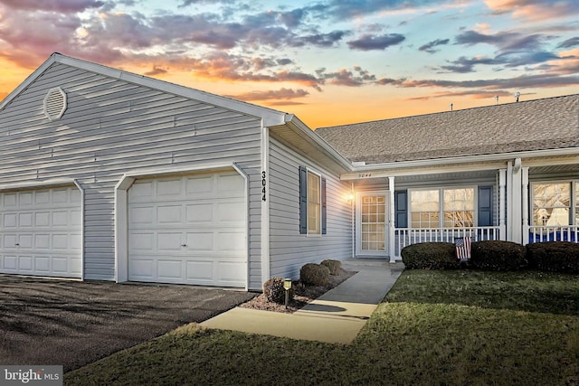 view of front of property with a garage, a porch, and aphalt driveway