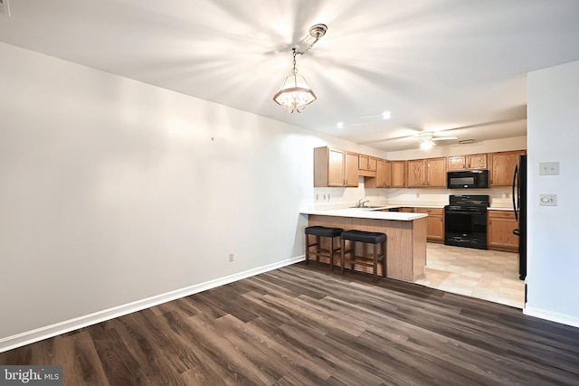 kitchen featuring baseboards, light countertops, a peninsula, and black appliances