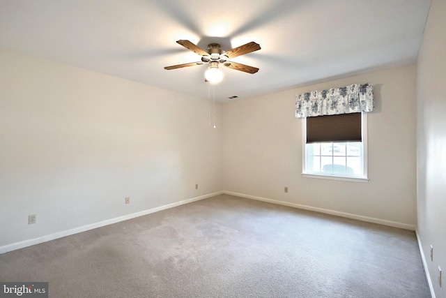 carpeted spare room featuring visible vents, baseboards, and a ceiling fan