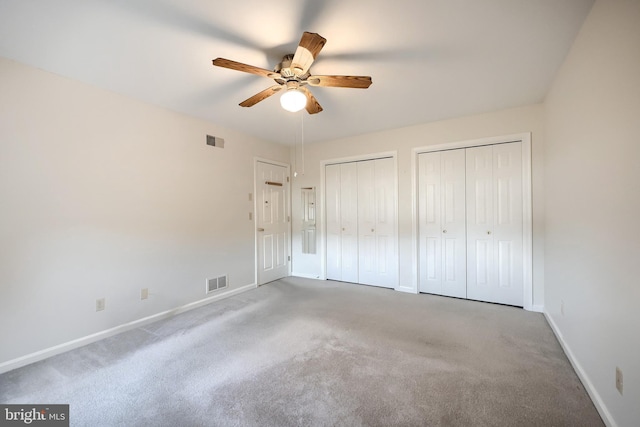 unfurnished bedroom with multiple closets, visible vents, carpet floors, and baseboards