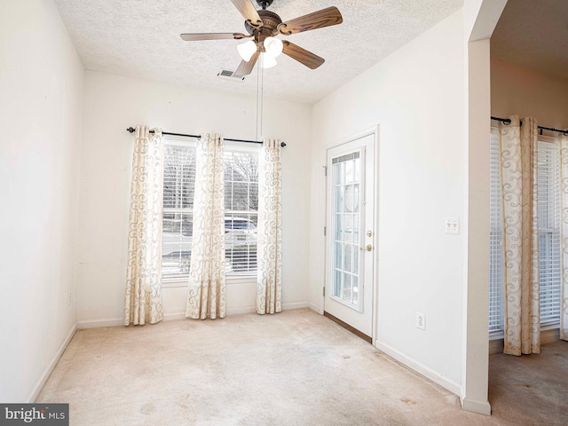 empty room featuring visible vents, a textured ceiling, carpet floors, baseboards, and ceiling fan