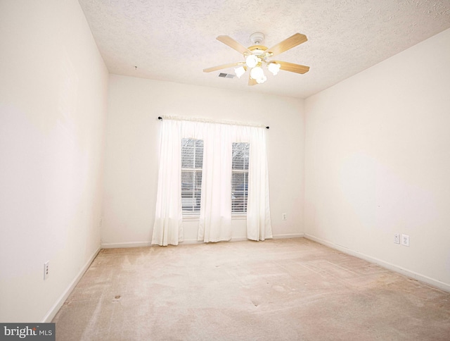 carpeted empty room featuring visible vents, baseboards, a textured ceiling, and ceiling fan