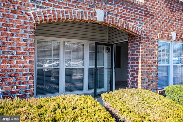 view of exterior entry featuring brick siding