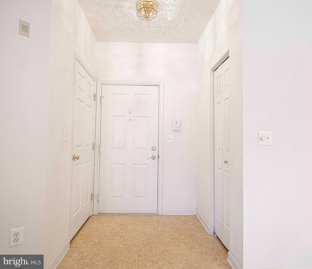 hallway with light floors and a textured ceiling