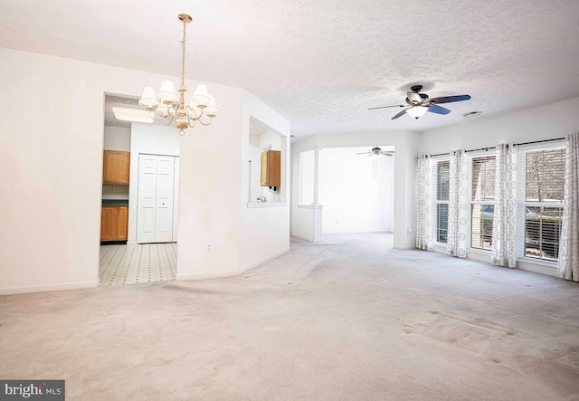 unfurnished living room with visible vents, baseboards, light carpet, ceiling fan with notable chandelier, and a textured ceiling