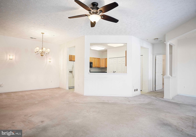 unfurnished living room featuring visible vents, a textured ceiling, baseboards, light colored carpet, and ornate columns