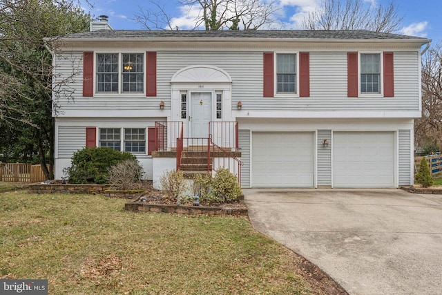 raised ranch with an attached garage, fence, a front yard, a chimney, and driveway