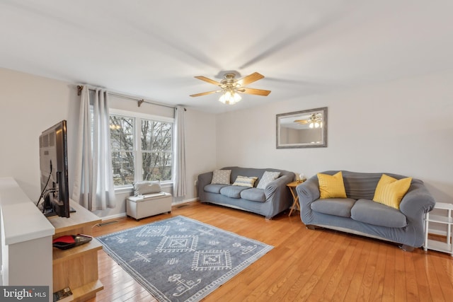 living area with baseboards, light wood-style flooring, and a ceiling fan